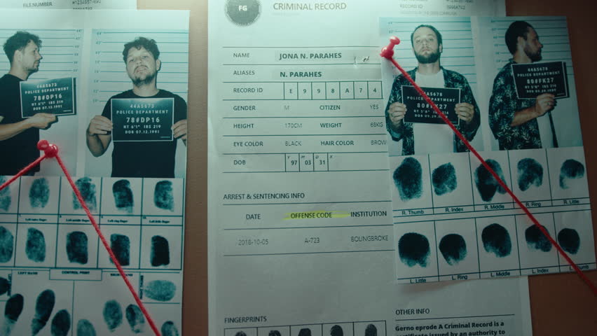 Mugshots of suspects, fingerprints and criminal record connected with red string pinned to the investigation board on the wall in the detective office. No people, close-up shot