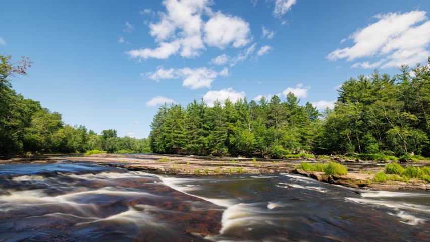 Time lapse of the clouds moving above Kettle River surrounded by forest in Minnesota.