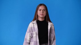 4k video of one girl with negative facial expression over blue background.