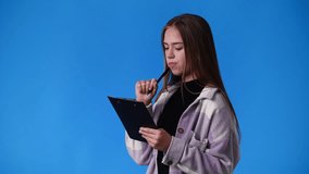 4k video of one girl taking notes over blue background.