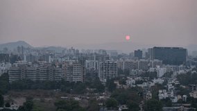 High angle cityscape view and day to night time lapse of an Indian metro city on a clear sky day, Maharashtra, India