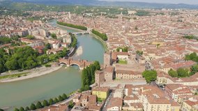 Inscription on video. Verona, Italy. Flying over the historic city center. Scaliger Bridge. Castelvecchio Castello Scaligero, summer. Arises from blue water, Aerial View, Departure of the camera