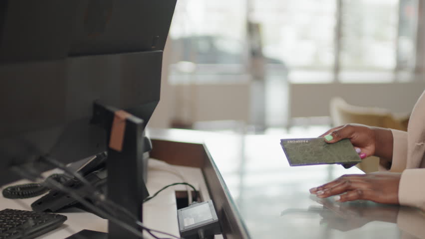 Medium shot of unrecognizable Black woman giving her passport to hotel receptionist for check-in Royalty-Free Stock Footage #1103601477