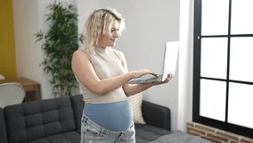 Young pregnant woman using laptop smiling at home - Powered by Shutterstock - Get 15% off with code: PIKWIZARD15