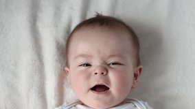 baby boy adorable newborn infant lying on bed looking up.mother kissing kid cheek,tenderness,caresses.toddler is talking something moving lips,close up face portrait 4k.woman hand on body, tongue out - Powered by Shutterstock - Get 15% off with code: PIKWIZARD15