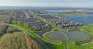 The Almere neighborhood is a modern and sustainable community that utilizes a solar panel island Zoneiland to partially power its district city heating system. Aerial video.