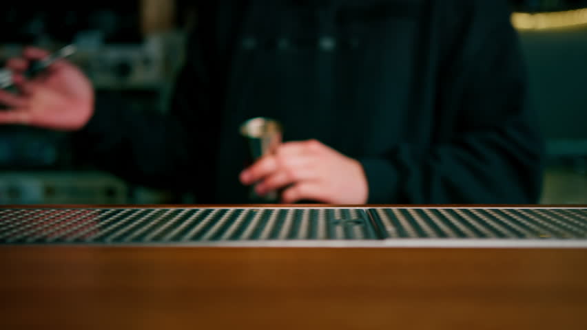 A professional bartender pours alcohol into a measuring cup The process of making cocktails in a club in bar close-up