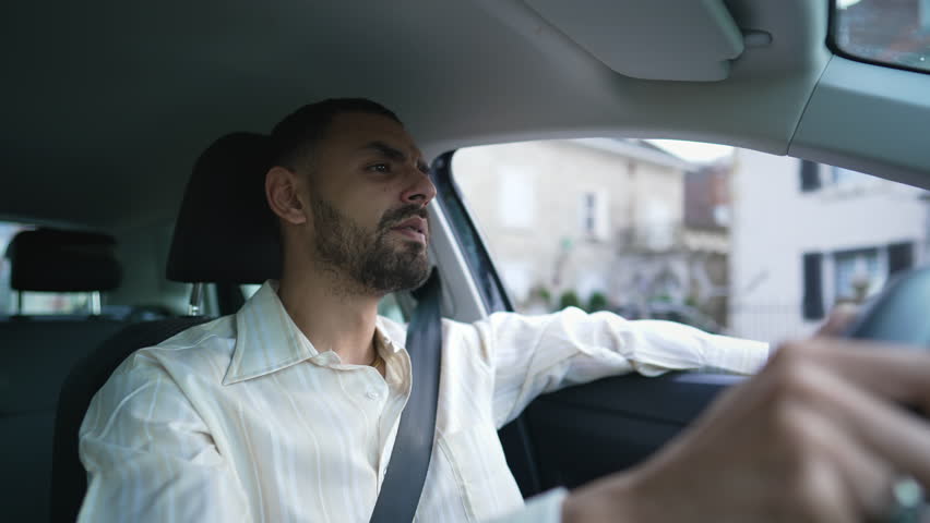 A focused Middle Eastern driver behind the wheel with a pensive expression. An Arab man driving car with care and attention. Interior shot of a young man holding steering wheel with a thoughtful look Royalty-Free Stock Footage #1103622885