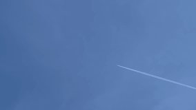 A long trail of airplane on blue sky. The plane flies in the blue sky and leaves a trail of condensation. Stock video. 4K