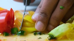 Close up clip of hand holding vegetables and knife cutting them finely to make salsa