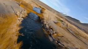 FPV drone footage of a stunning sunset aerial view of winding river in Chalk Hill, California. Colorful fall foliage and vibrant brush create a picturesque landscape.