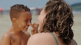 mother applying sunblock lotion on sons skin for sun protection little boy getting ready to swim on the beach with mom using sunscreen caring for childs health on sunny day 
 - Powered by Shutterstock - Get 15% off with code: PIKWIZARD15