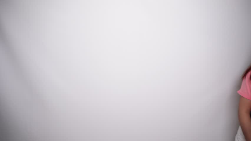 Smiling young Asian woman is wearing pink shirt, gesturing traditional greeting in Studio with White background