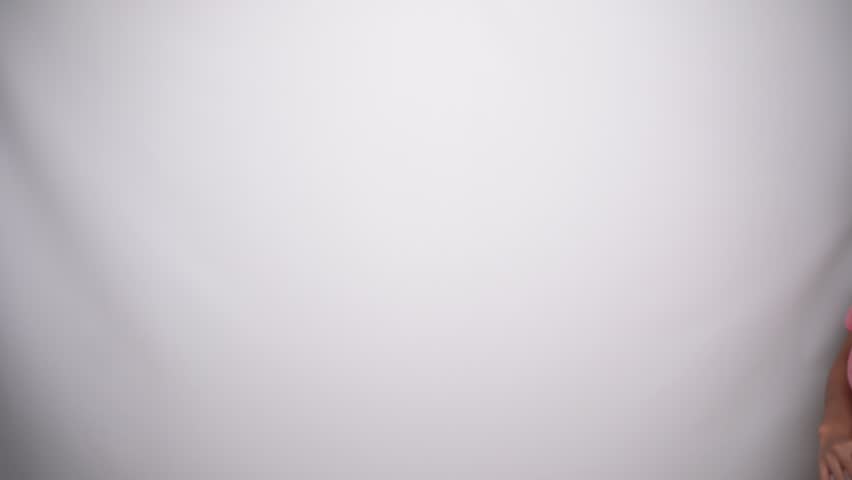 Smiling young Asian woman is wearing pink shirt, gesturing traditional greeting in Studio with White background