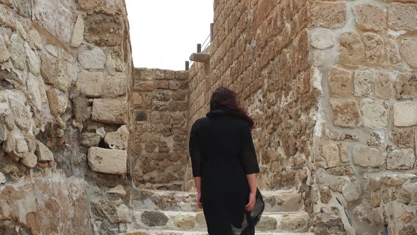 Woman in arabian black hijab walks upstairs ruin ancient Fort Bahrain, rear view. Ancient fortress archaeological site stones, conservation traditions culture. Tourism, travel, tour, rear back view. Royalty-Free Stock Footage #1103640857