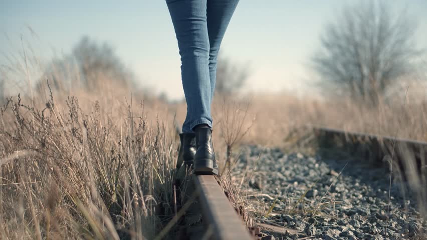 Tourist Legs Walking On Railway Middle Of Rail.Lonely Woman Feet In Jeans Walking On Rail Road When Train Or Tram Cancelled.Girl Walks To Home On Railroad Tracks After Canceled Tram Public Transport 