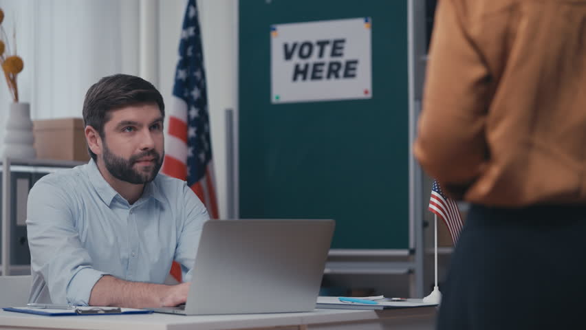 US polling station employee processing voters on election day, checking ID Royalty-Free Stock Footage #1103644553