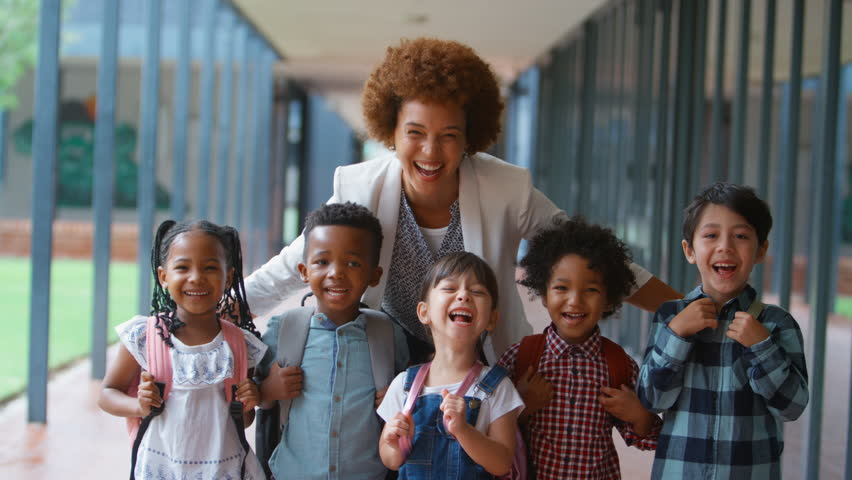 Portrait of class of multi-cultural elementary school students with female teacher standing on outside walkway by school building - shot in slow motion Royalty-Free Stock Footage #1103649063
