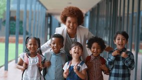 Portrait of class of multi-cultural elementary school students with female teacher standing on outside walkway by school building - shot in slow motion - Powered by Shutterstock - Get 15% off with code: PIKWIZARD15
