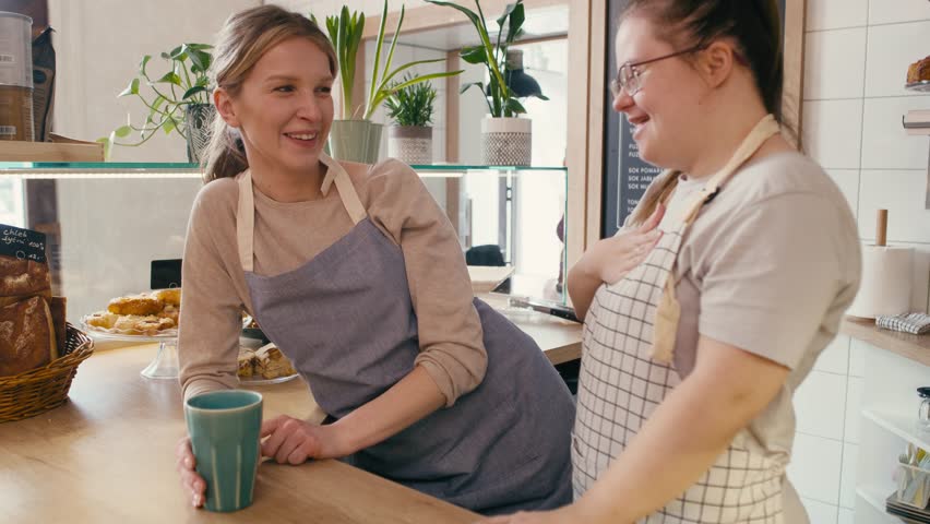 Down syndrome girl chatting with her workmate in the cafe. Shot with RED helium camera in 8K.  Royalty-Free Stock Footage #1103650783