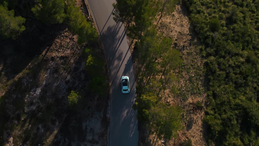 Modern car road trip driving along a street. Scenic Serra de Tramuntana with green hills. Palma de Mallorca Island hiking and nature natural landscape on Majorca. Cinematic vacation. Aerial drone 4K.