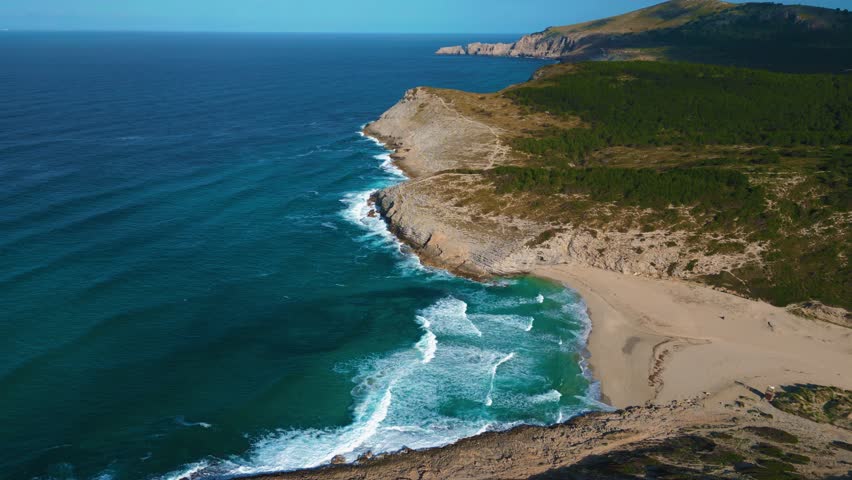 Beautiful beach bay with clear turquoise sea water, green hills, white sand. Serra de Tramuntana, Palma de Mallorca Island. Balearic Majorca seaside coast. Cinematic vacation. Aerial drone 4K UHD.