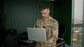 Soldier working with laptop in home. Everyday life of a military man in reserve. Work and communication online