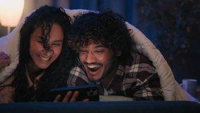 Multiracial couple man and woman laughing smiling happy cover heads with blanket under duvet at night evening home using mobile phone watching online movie browsing smartphone laugh fun gadget addict - Powered by Shutterstock - Get 15% off with code: PIKWIZARD15