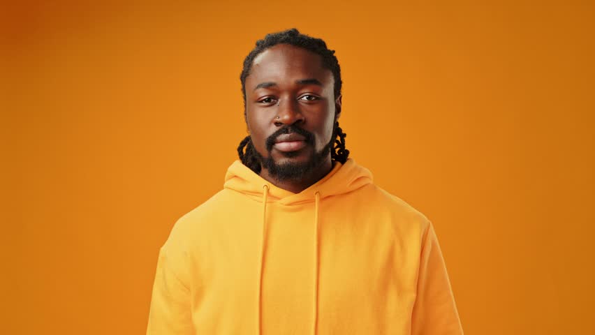 Portrait of shocked young African man on yellow background