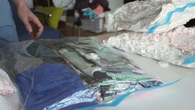 Close-up of unrecognizable man sucking air from vacuum compression bag with clothes using vacuum cleaner for storage in closet, slow motion. Concept of space saving and careful storage of outerwear. - Powered by Shutterstock - Get 15% off with code: PIKWIZARD15