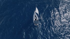 Aerial Cenital Shot of a Yacht Setting Sail, Followed by a Smooth Tilt Up Shot that Reveals the Vast and Open Sea, Inviting Adventure and Exploration.