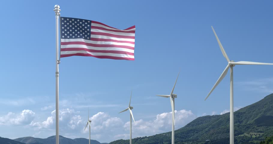 The National Flag of the USA (United States of America) flies gracefully over a blue sky with a beautiful mountain in the background and a row of wind turbines 
