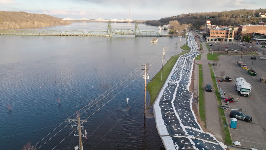 Large sandbag barrier along flooded river protects city infrastructure from water damage