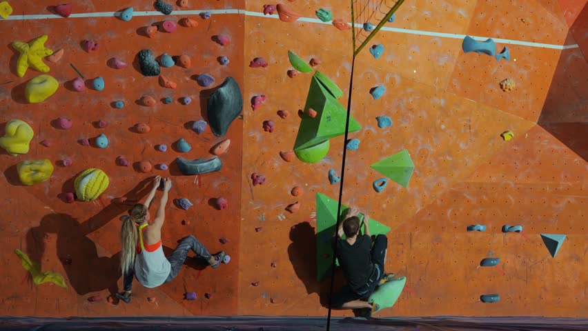 A beautiful shot from a joint training session of a man and a woman of millennials who climb a climbing wall without insurance together side by side. Competition of men and women on the climbing wall Royalty-Free Stock Footage #1103679515