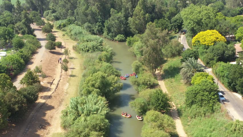 Aerial people exploring Jordan river, drone flying forward over green plants - Aerial view of Jordan river