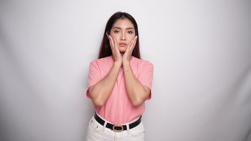 Shocked Asian woman is wearing pink shirt with her mouth wide open in Studio with White background