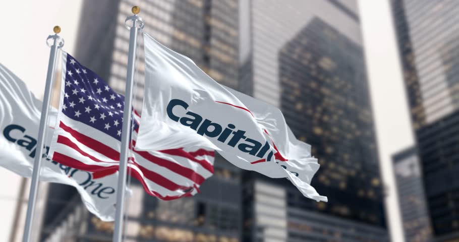 New York, US, April 2023: Capital One bank and US flags waving in a financial district.  Seamless 3d render animation. Slow motion loop. Selective focus. Fluttering fabric. Close-up