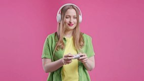 Young teenager girl playing online video game, console TV with joystick on pink