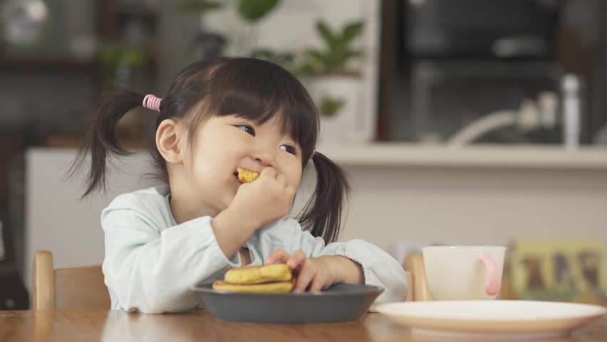 Asian child eating pancakes at home
