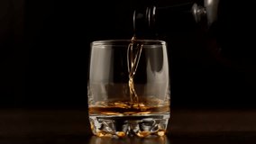 Bourbon Pouring In Slow Motion.Running Brandy In Glass From Bottle.Cognac Pouring In Glass Slow Motion.Golden Whiskey In Goblet Floats On Black Background. Rum Flowing From Brown Bottle. Drink Concept - Powered by Shutterstock - Get 15% off with code: PIKWIZARD15