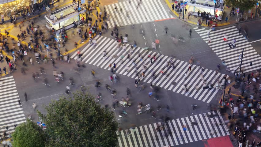Cars pass by, and the intersection is filled with people crossing street, time lapse shot from above. Scramble crosswalk at Shibuya in busy evening hour, busy life at modern and big Asian city Royalty-Free Stock Footage #1103703785