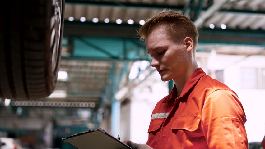 Close-up hand male mechanic Caucasian, male mechanic wears clothes work in large workshop, for safety protection against dirt, Checking condition wheels car that has some abnormalities.