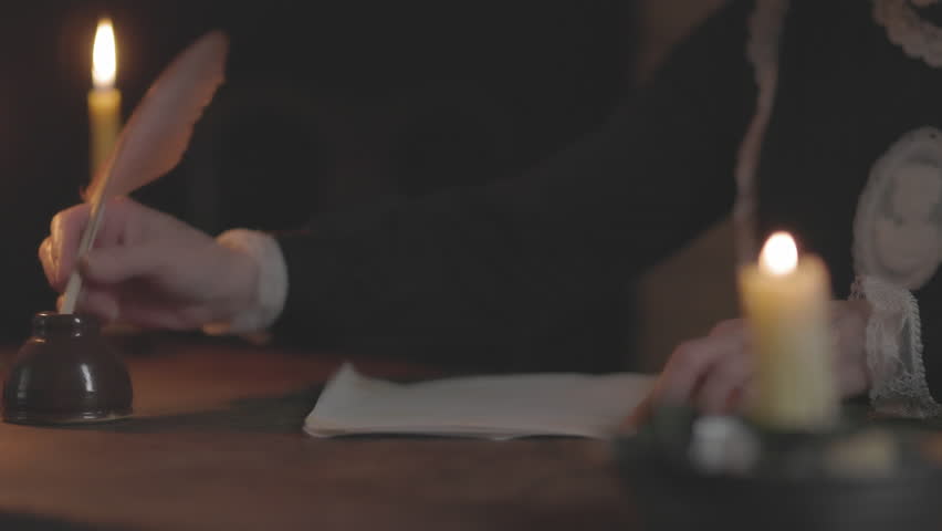 A candlelit scene from the 1790s of a woman writing a letter with a quill pen with the main focus being on the inkwell. Royalty-Free Stock Footage #1103709183