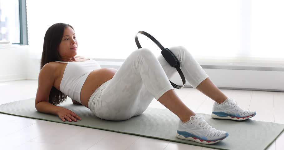 Prenatal exercises. Pregnant woman training doing pelvic exercise and thigh workout lying down on yoga mat. Portrait of expectant mother and pregnancy belly doing bodyweight training at home Royalty-Free Stock Footage #1103719405