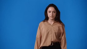 4k video of one girl pointing at left and showing thumb up over blue background.