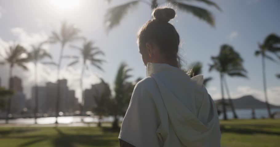 Young woman doing yoga and meditation outside on the grass with palm trees in Hawaii