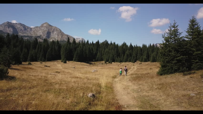Woman with son walking on the hills with the aerial view of Durmitor National Park, Montenegro 
 | Shutterstock HD Video #1103726331