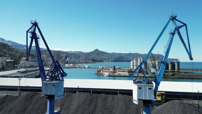 This breathtaking drone video captures a stunning view of the city and mountains from between two massive cranes.