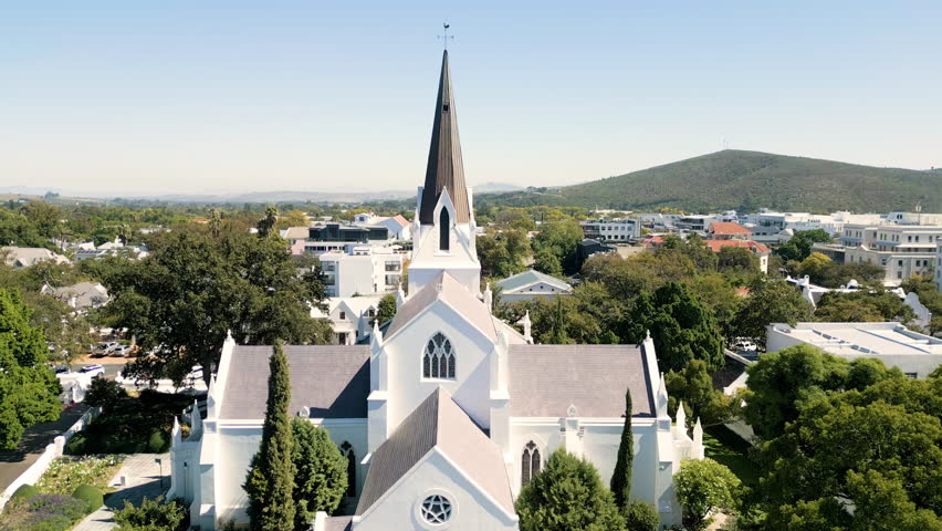 Church spire and church building, NG Kerk aerial dolly towards spire, with residential houses and apartments of the town, Stellenbosch, South Africa