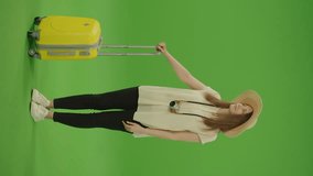 Vertical Video. Green Screen. Chroma Key. Happy Woman Traveller in Hat with Luggage Looking Around and Posing on Camera, Standing Smiling. Female on Vacation Trip